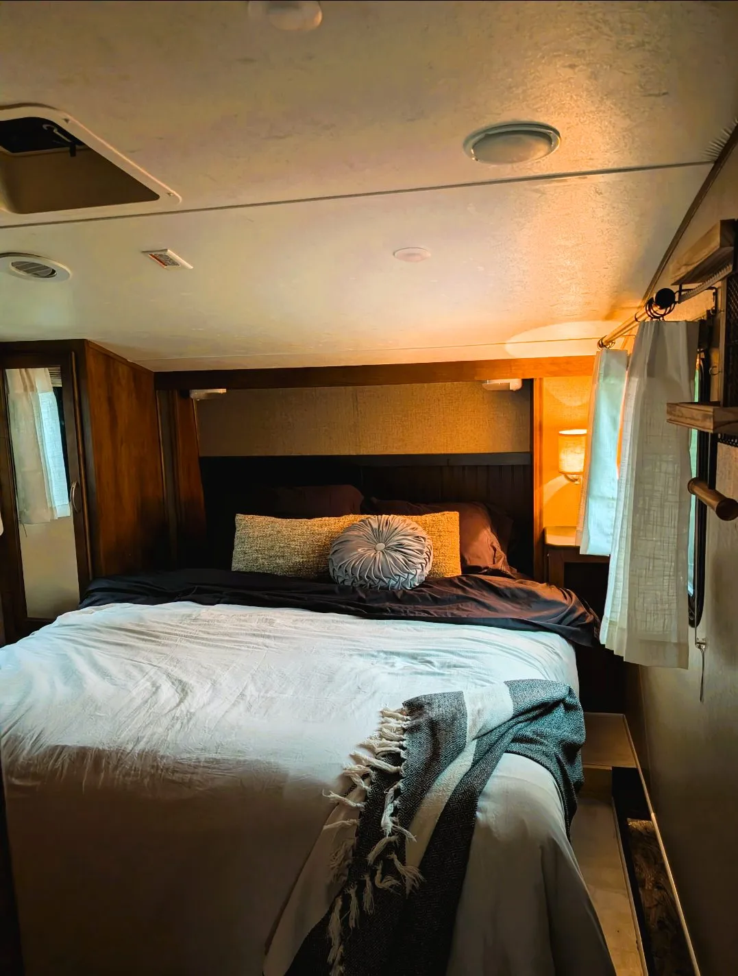 Inside the rental camper: the bedroom with a made-up bed under warm lights