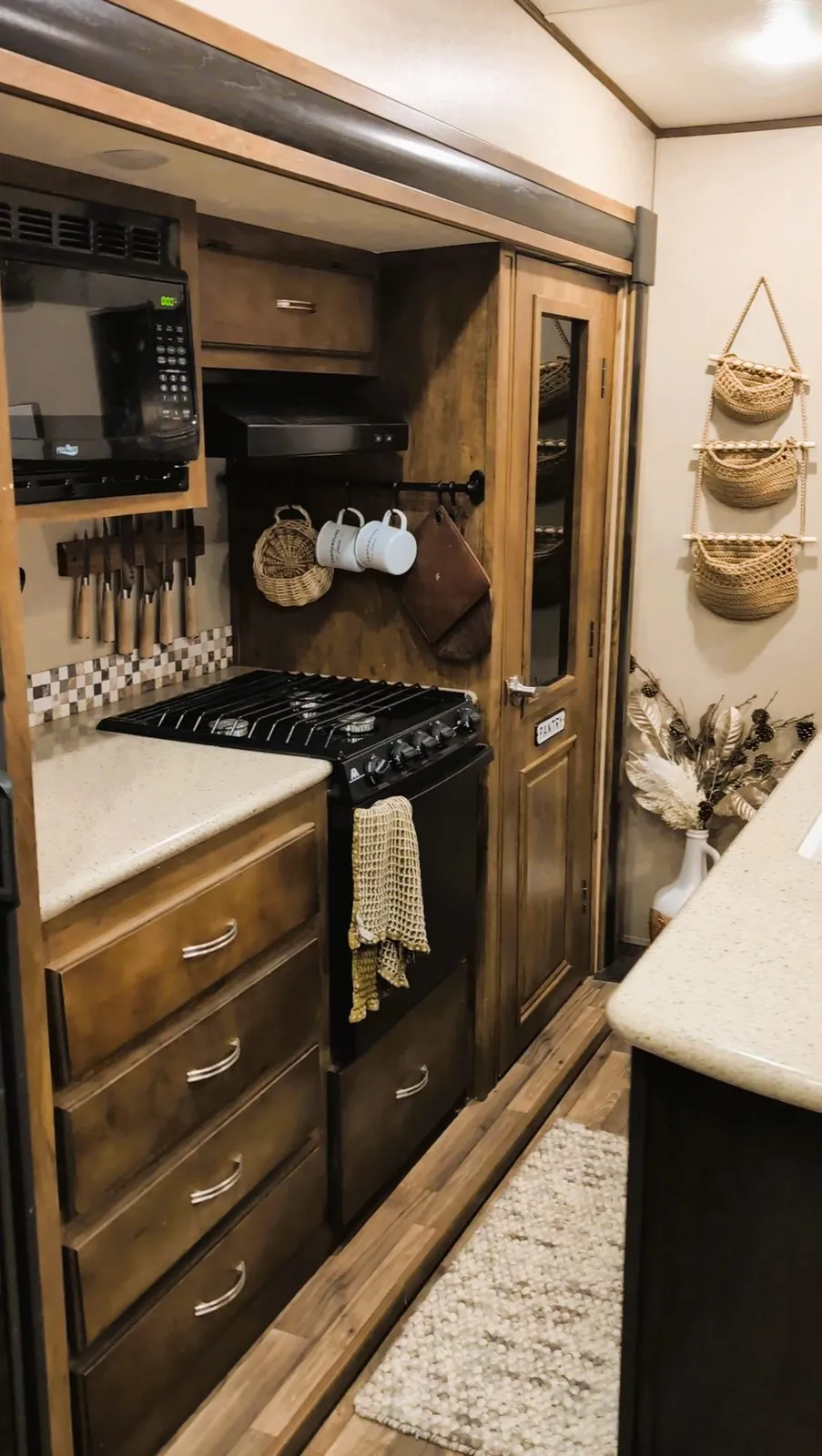 Inside the rental camper: the kitchen with a stove, a microwave and mugs on hooks