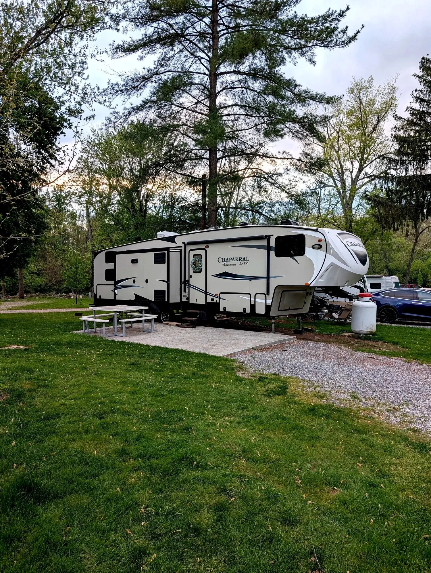 The rental fifth-wheel camper parked on its pad among pine trees