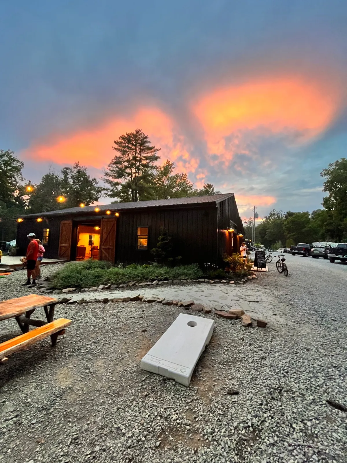 The rec room at sunset with picnic tables and a cornhole board out front