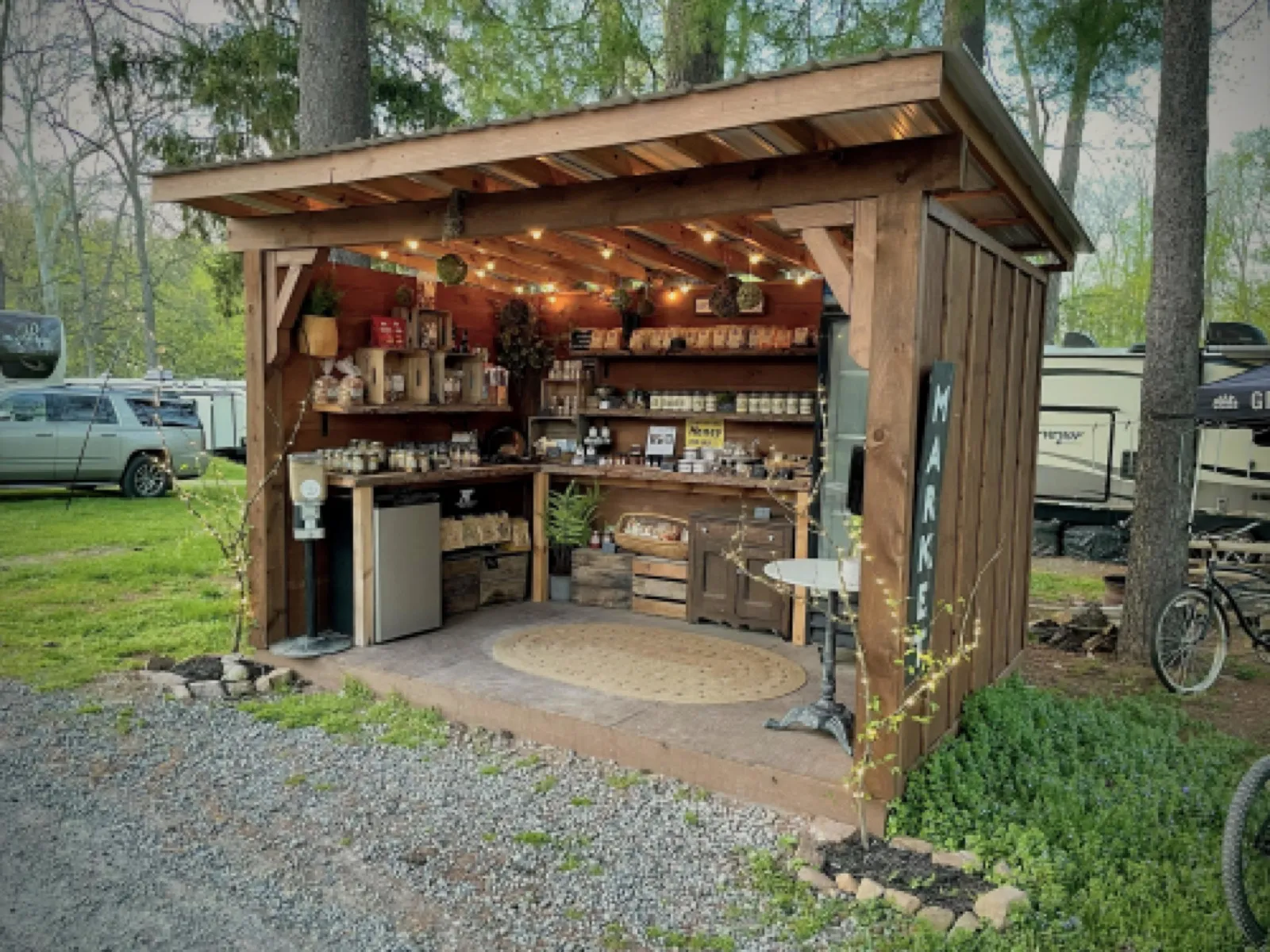 The open-front market stand under string lights, its shelves stocked with jars and baked goods