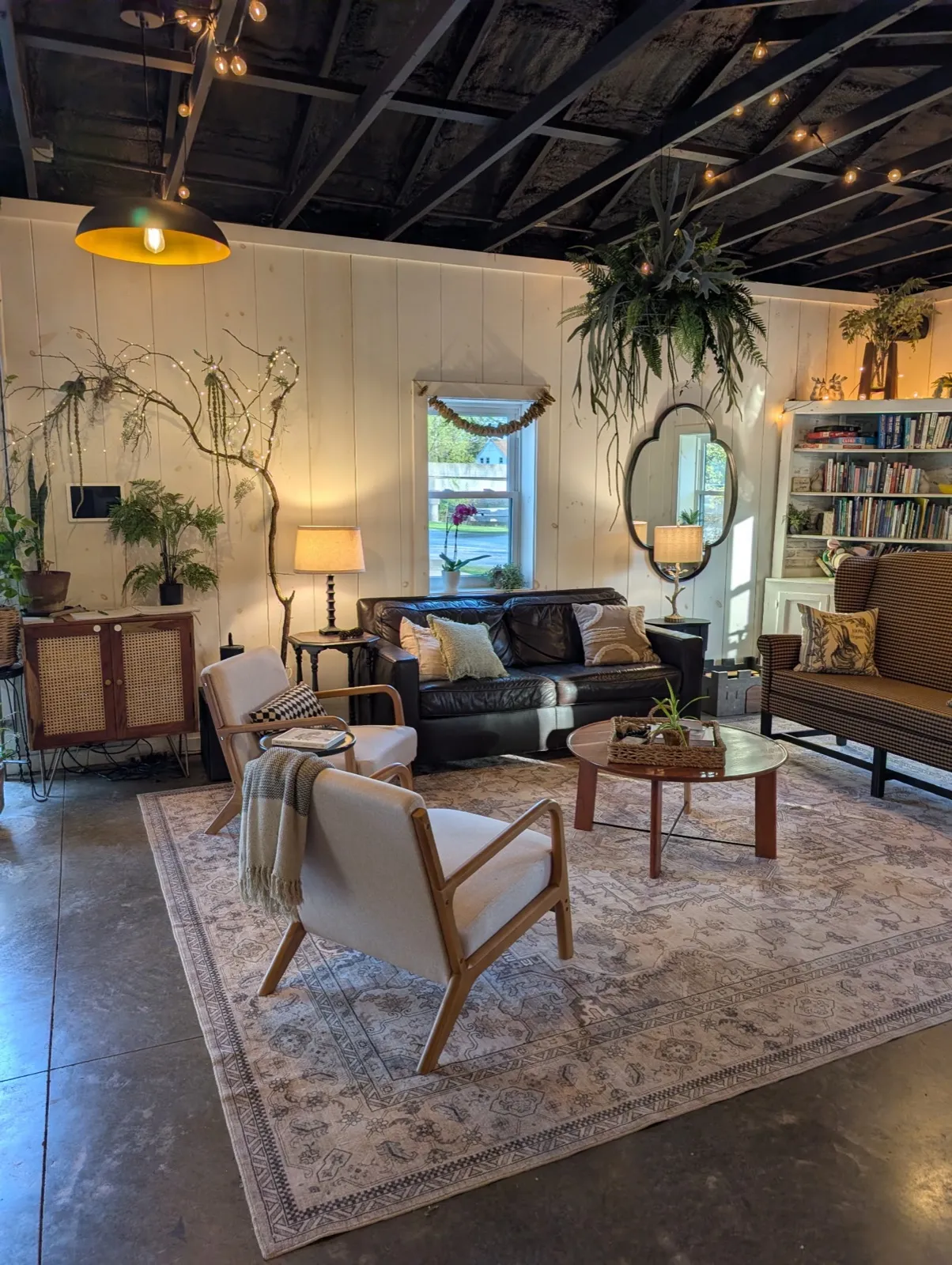 The rec room lounge with a leather sofa, armchairs and a patterned rug by the bookshelves
