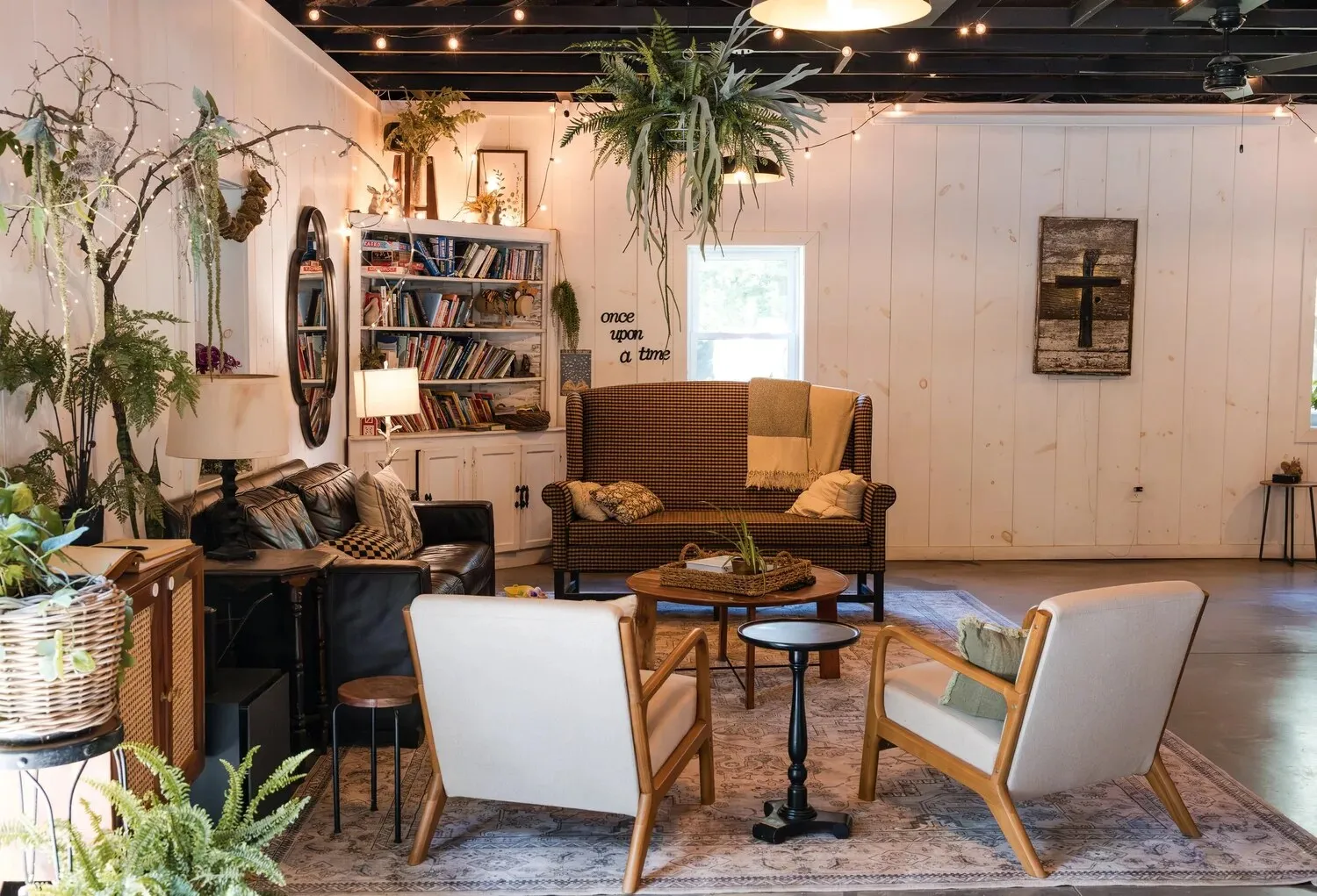 The rec room lounge with a sofa, armchairs, bookshelves and hanging plants