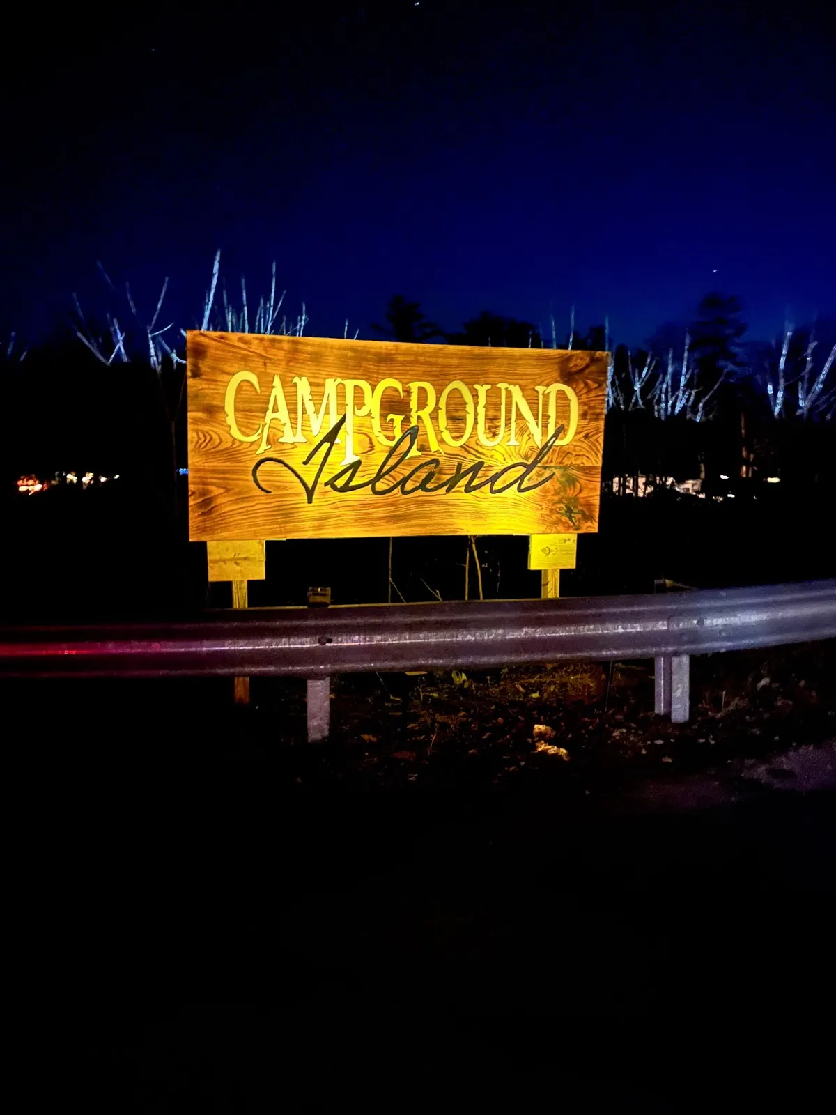 The lit Campground Island sign glowing at the entrance at night